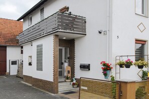A two-story building with a balcony, a door, and a small window.