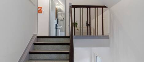 A staircase with a wooden handrail leading to a bathroom with a toilet and sink.