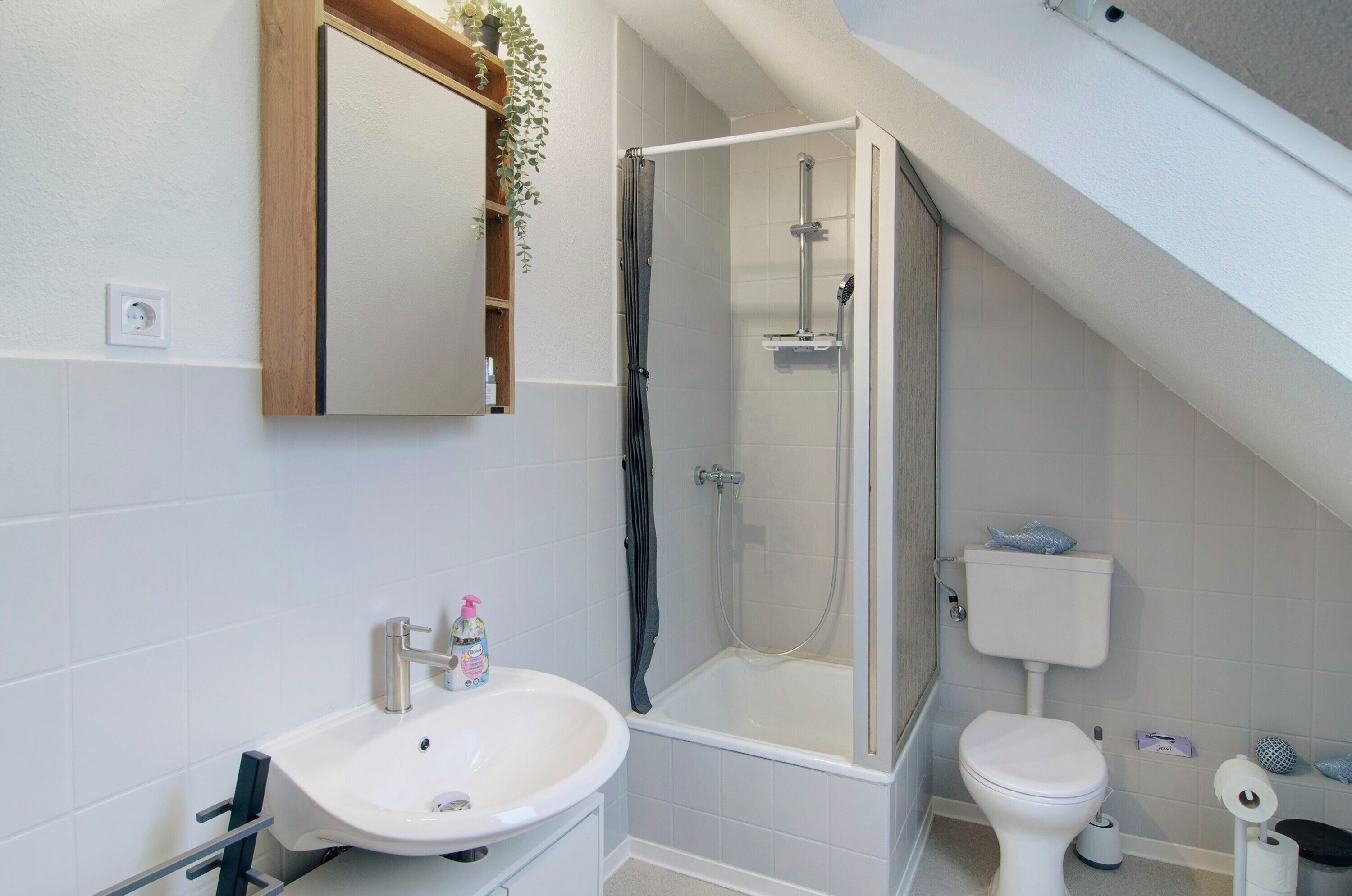 A bathroom with a shower, toilet, sink, and a mirror.