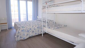 Une chambre avec un lit superposé, une table de chevet, une lampe et une fenêtre avec des rideaux.