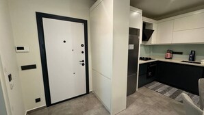 A compact kitchen with a white door, a built-in oven, and a small countertop. - Modern Comfort in Oba: New 1+1 Apartment in Sol Garden (Alanya)