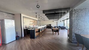 A modern kitchen with a central island, bar seating, and a stone accent wall. - Modern Comfort in Oba: New 1+1 Apartment in Sol Garden (Alanya)