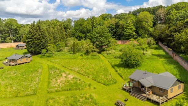 Un chalet doté de plusieurs cabanes, entouré d’une végétation luxuriante et d’arbres.