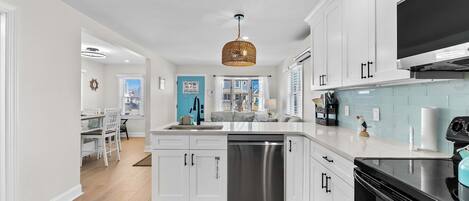 A modern kitchen with white cabinetry, a stainless steel dishwasher, and a black stove.