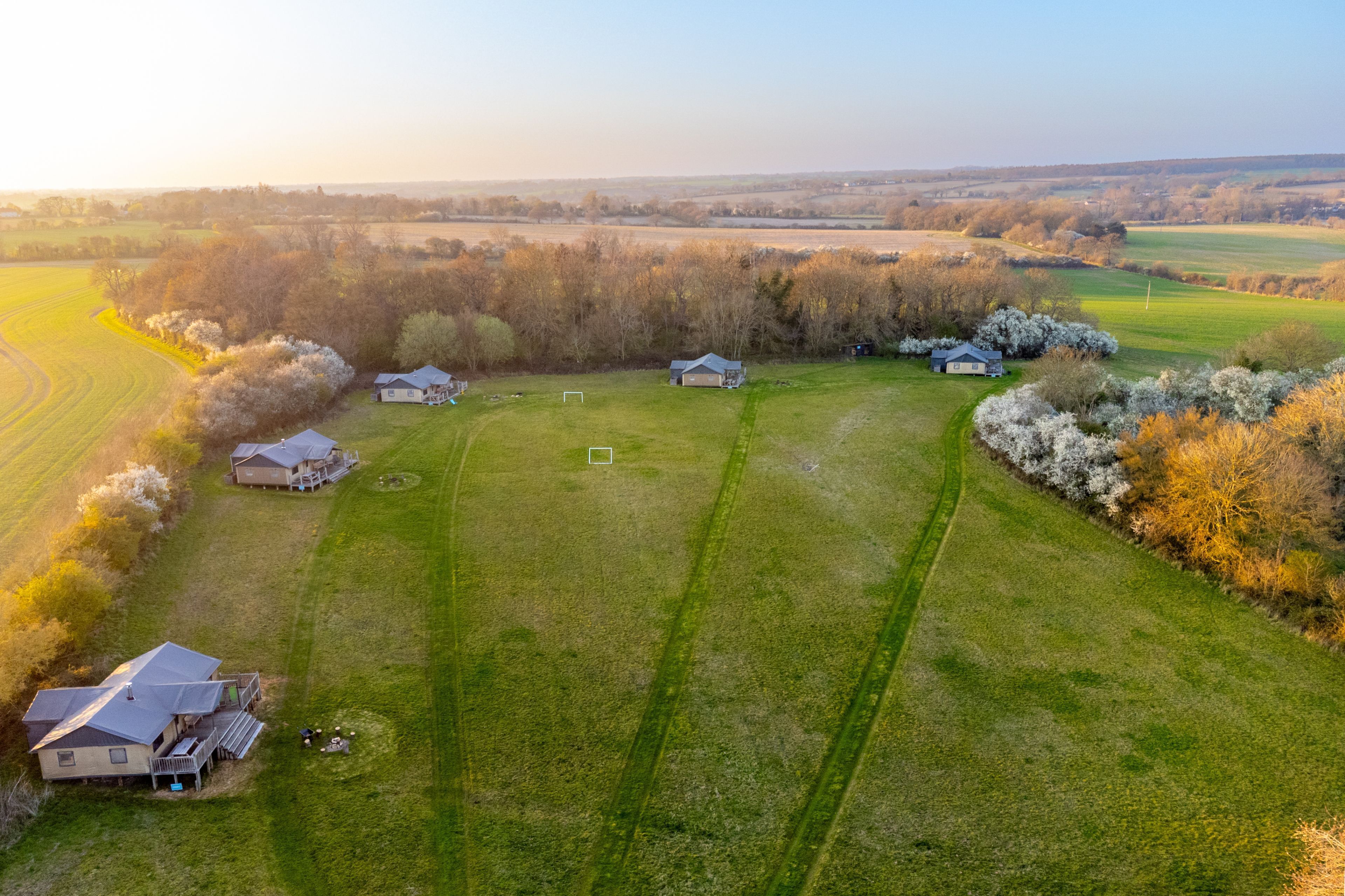 An aerial view of a rural property with several houses, green fields, and trees.