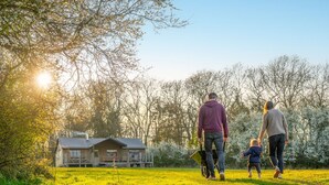 A family walking on a grassy field with a house in the background. - Dog friendly Safari Tent, Swallow at Sweffling Hall, Suffolk (Saxmundham)