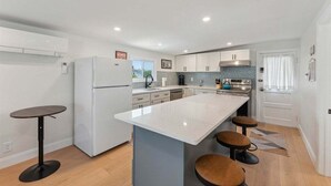 A modern kitchen with a central island, bar stools, and a refrigerator.