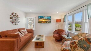 A living room with a sofa, armchair, coffee table, and a painting on the wall.