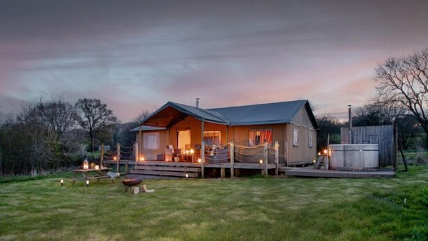 A rustic cabin with a porch, outdoor seating, and a fire pit. - Nuthatch at Kittisford Barton in Somerset with hot tub (Wellington)