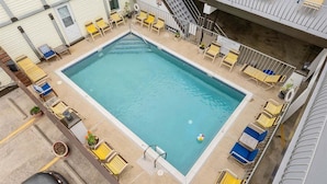 A rectangular pool with a surrounding deck area, including lounge chairs and a small staircase. - Top-Floor Studio with a Heated Pool & Parking (Wildwood)