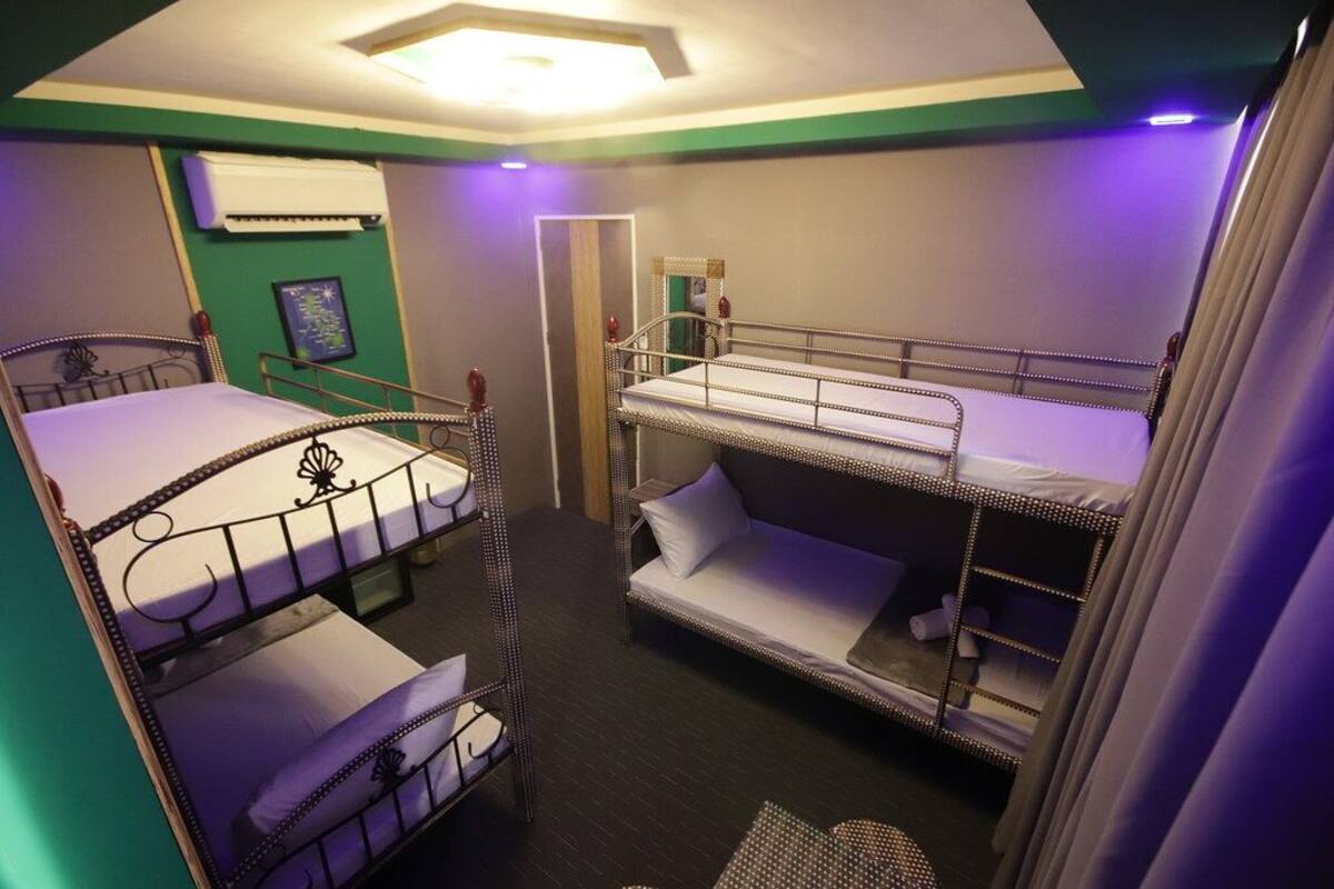 A room with bunk beds, a ceiling light, an air conditioning unit, and a framed picture on the wall.