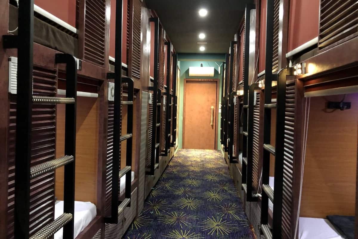 A narrow hallway with bunk beds on either side, leading to a door at the end.