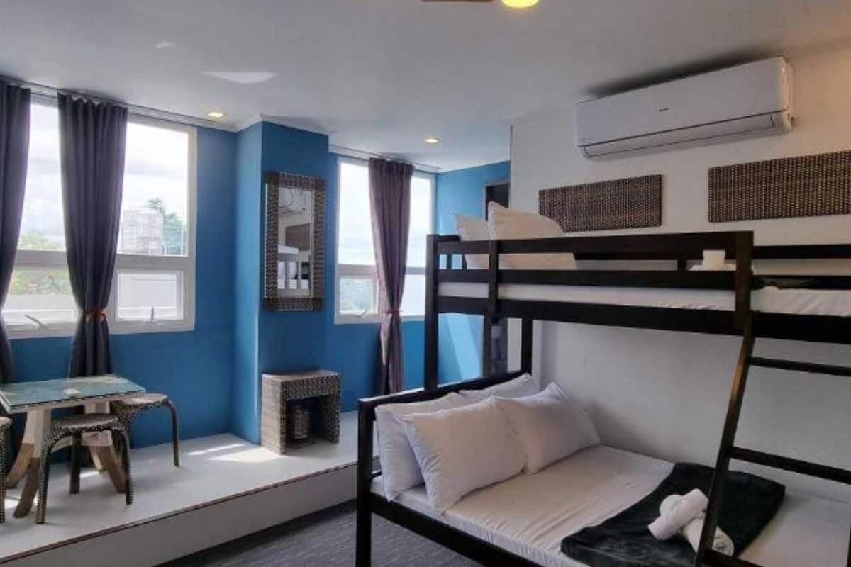 A bunk bed room with a desk and chair, a window with curtains, and an air conditioning unit.
