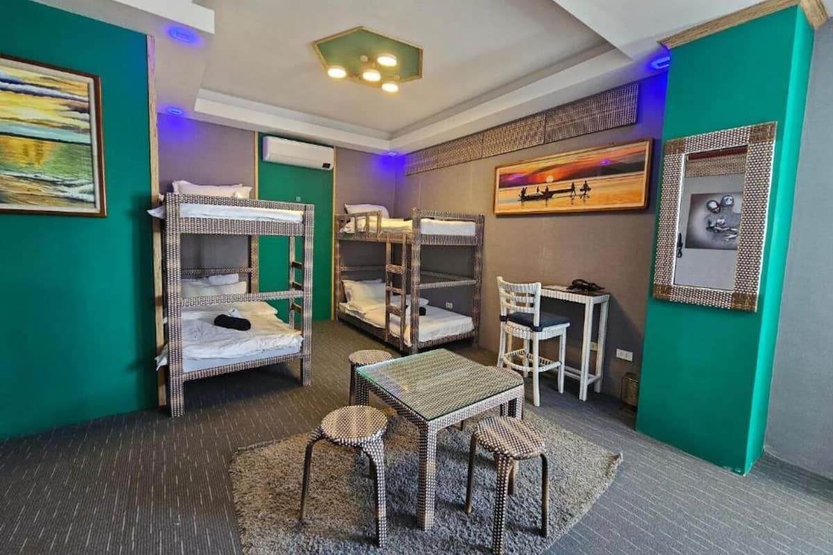 A room with bunk beds, a small table, chairs, and artwork on the walls.