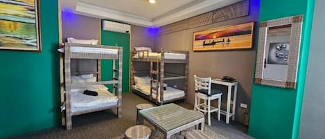 A room with bunk beds, a small table, chairs, and artwork on the walls.