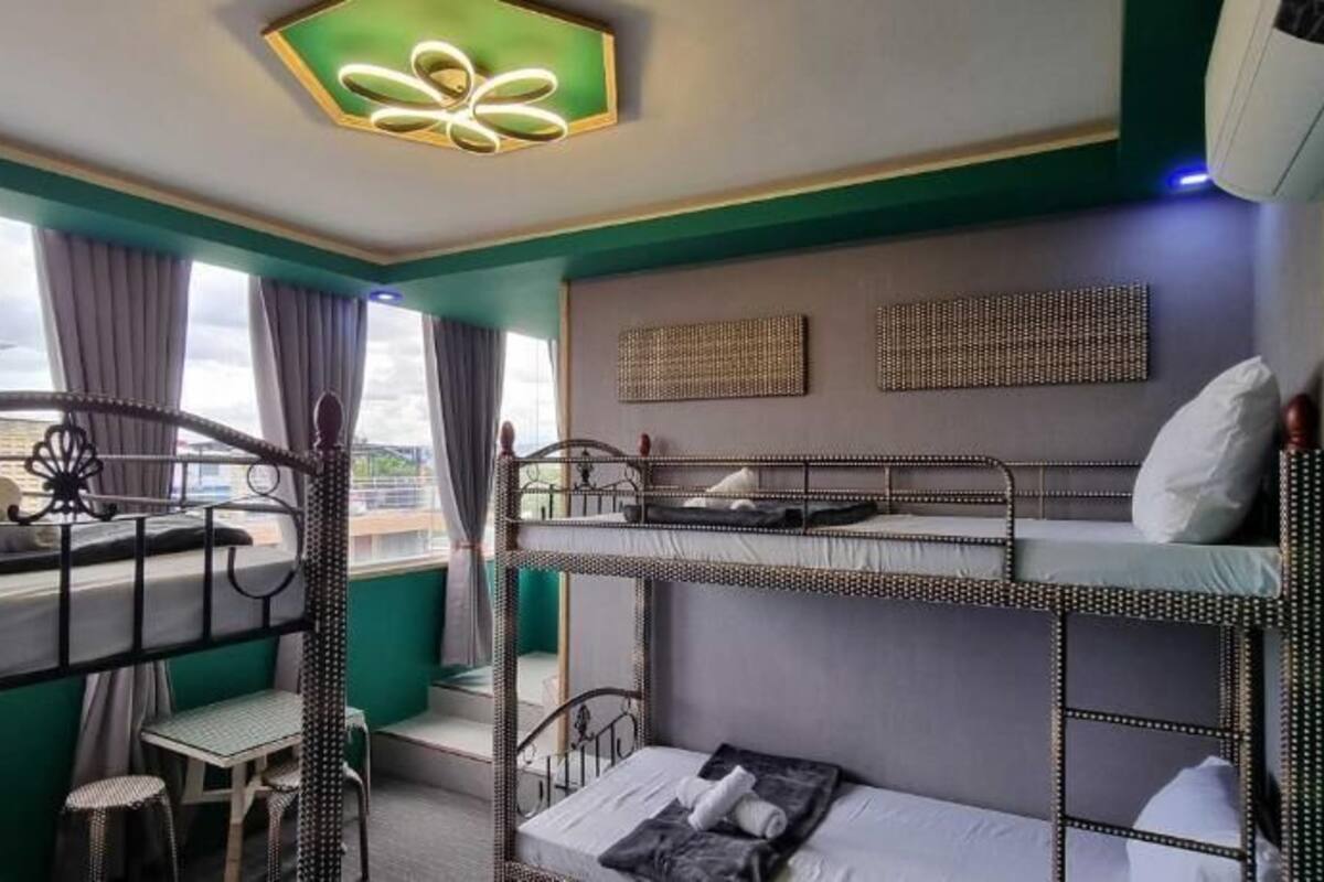 A bunk bed room with a view of the city, a small table, and a ceiling light fixture.