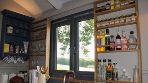 A kitchen with a wooden countertop, a copper faucet, and shelves with glassware and bottles. - Top Farm Shepherds Lodge, nestled in a peaceful farm in Marsham, North Norfolk (Marsham)