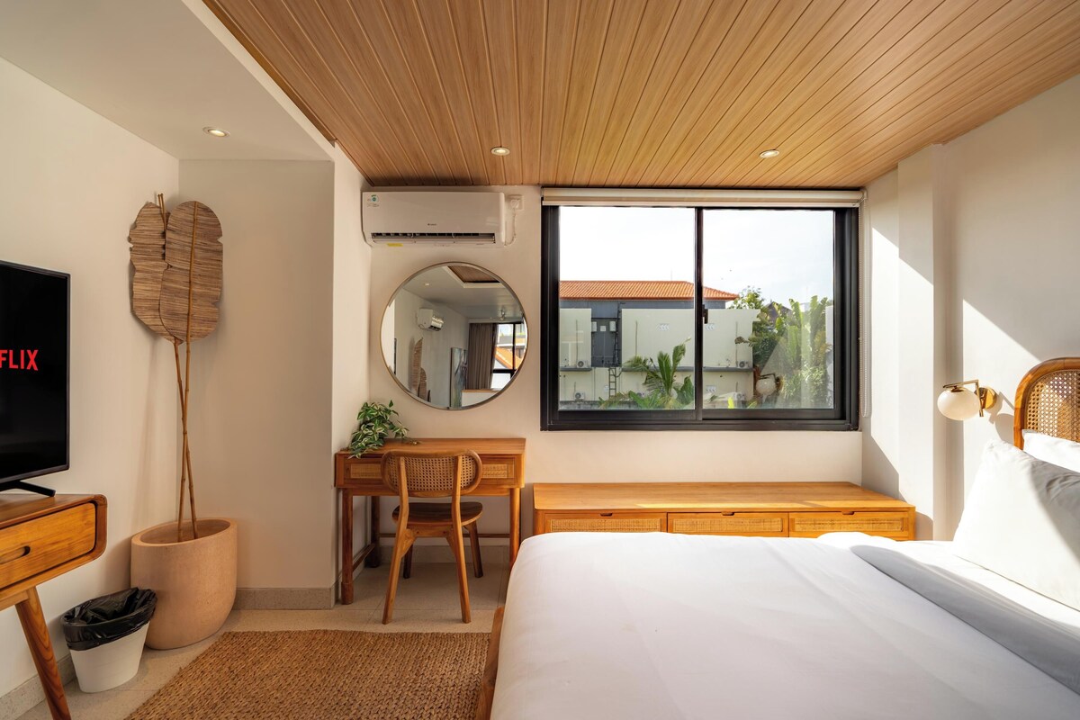 Een slaapkamer met een bed, een bureau, een stoel, een televisie en een raam met uitzicht.