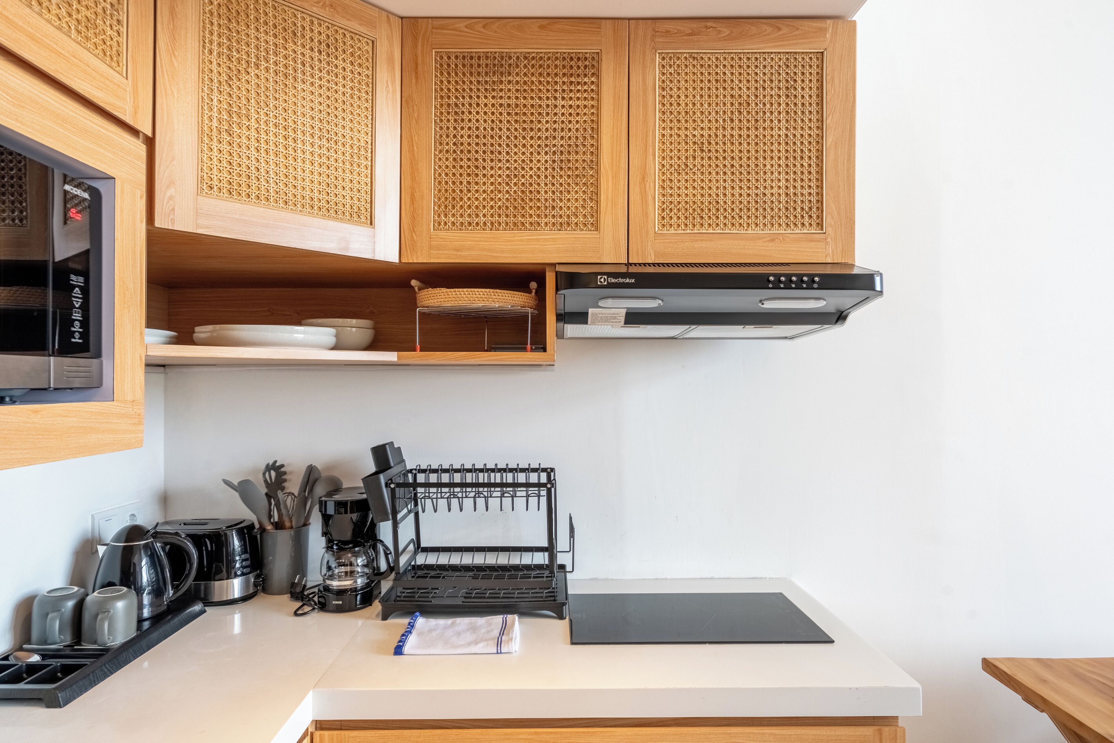 A kitchen with wooden cabinets, a coffee maker, a kettle, and a toaster.