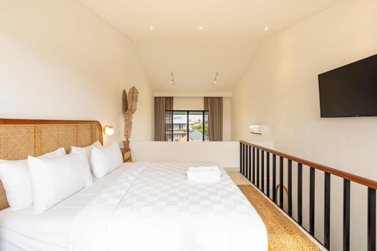 Een hotelkamer met een groot bed, een flatscreen televisie aan de muur en uitzicht door het raam.