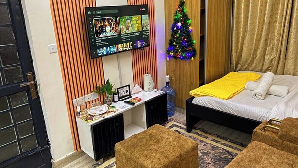 Une chambre d’hôtel avec un lit, un bureau doté d’un téléviseur à écran plat, un petit sapin de Noël et une fenêtre avec des rideaux.