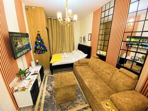 Une chambre d’hôtel équipée d’un lit, d’un canapé, d’une télévision, d’un sapin de Noël et d’un mini-bar.
