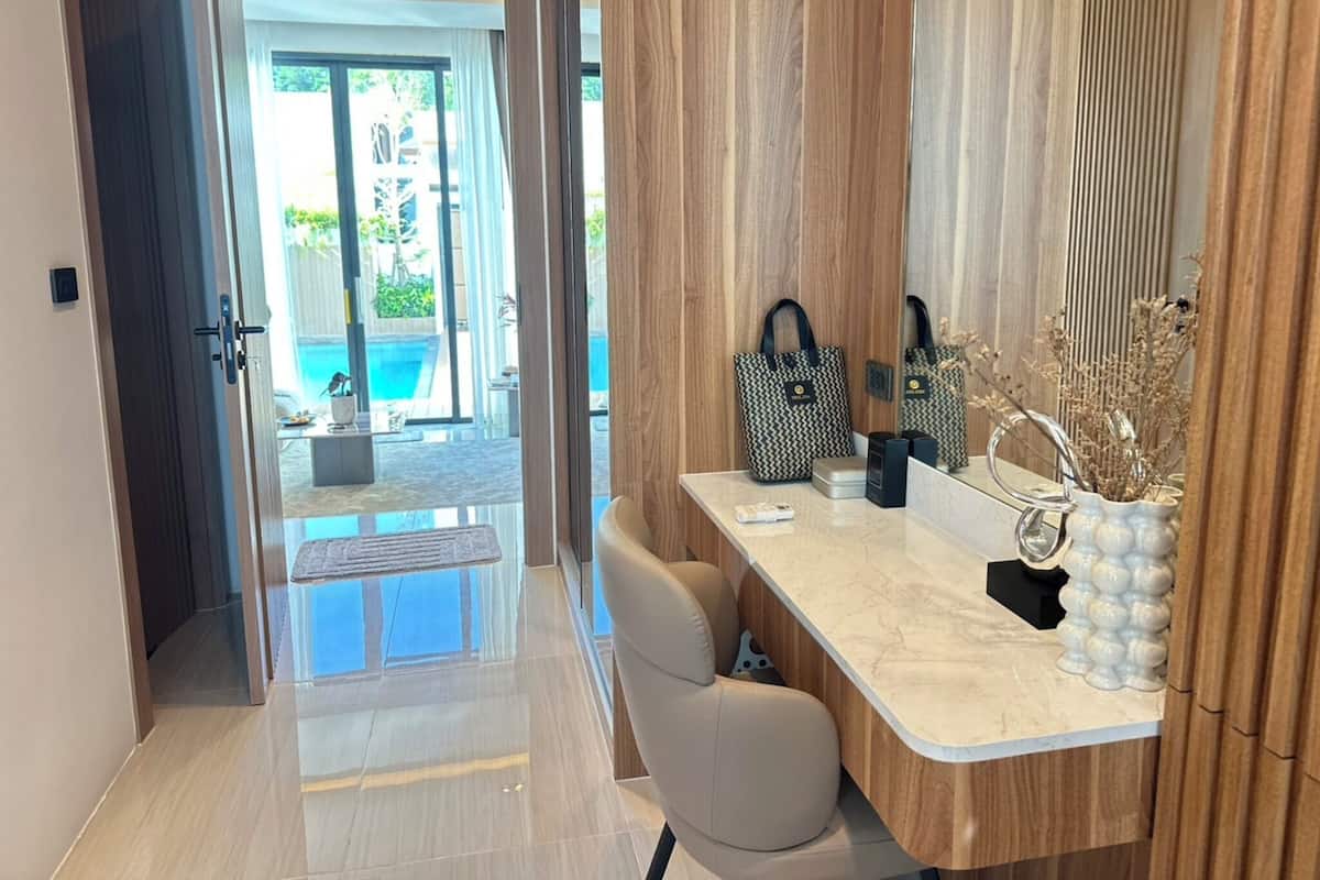 A modern bathroom with a marble countertop, a sink, and a mirror. There is a wooden panel wall and a view of an outdoor pool area.