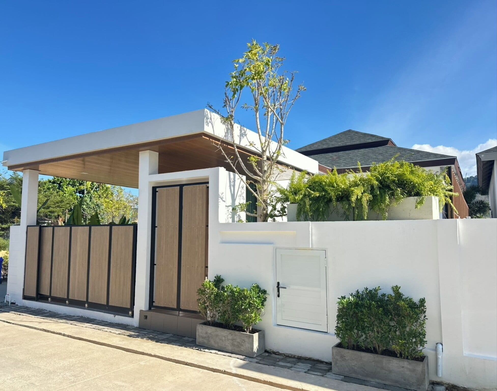 A modern house with a covered porch, a white exterior, and a wooden gate.