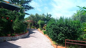 Un chemin pavé mène à un bâtiment doté d’un mur en pierre et agrémenté de plantes en pot.