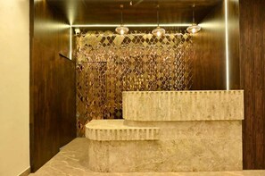 A modern bathroom with a marble sink, a decorative wall with a diamond pattern, and three pendant lights.