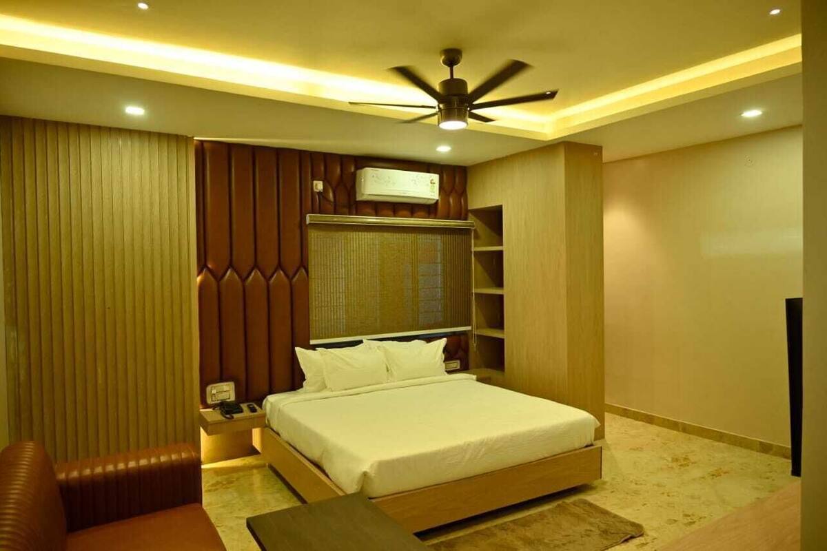 Un dormitorio con cama, mesita de noche, escritorio, silla, ventilador de techo y estanterías empotradas.