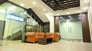 A modern lobby with a staircase, a tufted sofa set, and a ceiling fan. - Vastu Inn (Rourkela)