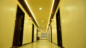 A long, well-lit hallway with doors on both sides, leading to a large window at the end. - Vastu Inn (Rourkela)