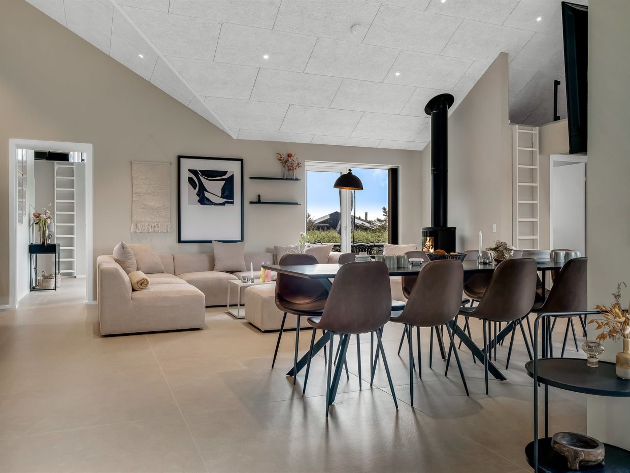 A spacious living room with a large window, a fireplace, and a dining area with modern chairs and a table.