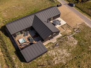 Ett modernt hus med en stor terrass, utomhusmöbler och en bubbelpool.