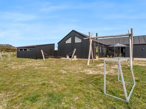 Un bâtiment moderne doté d’une grande entrée, d’un espace extérieur aménagé avec des sièges et d’une cour verdoyante.