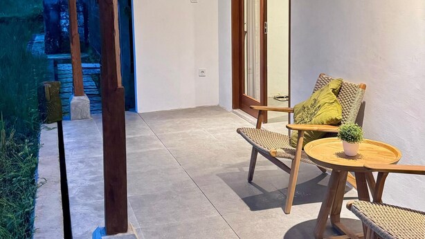 A covered outdoor patio with a seating area, a wooden table, and a potted plant. - Rumah Kemuning Bali (Bali)
