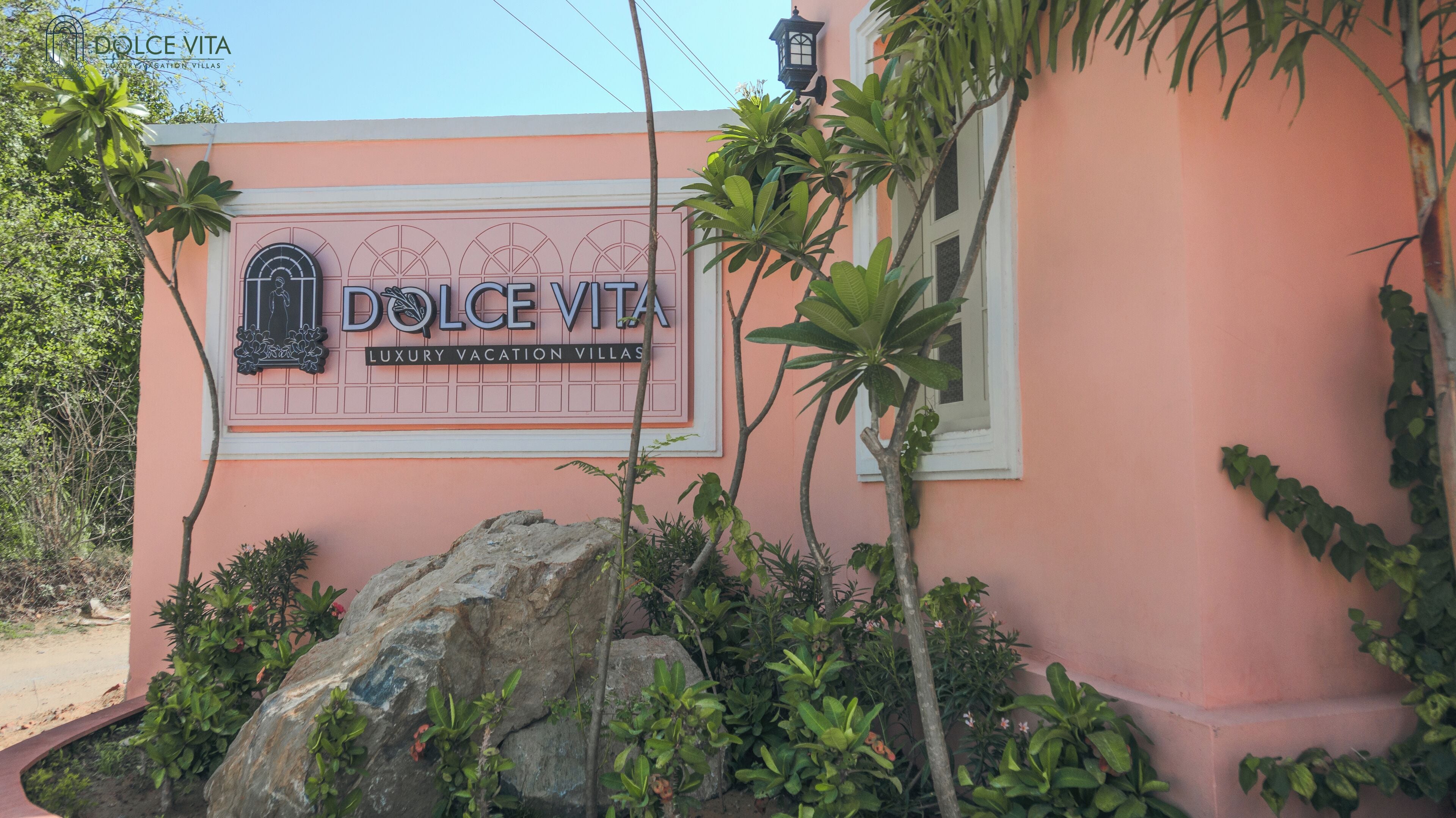 Une enseigne pour « Dolce Vita Luxury Vacation Villas », avec une fenêtre décorative et un mur rose.