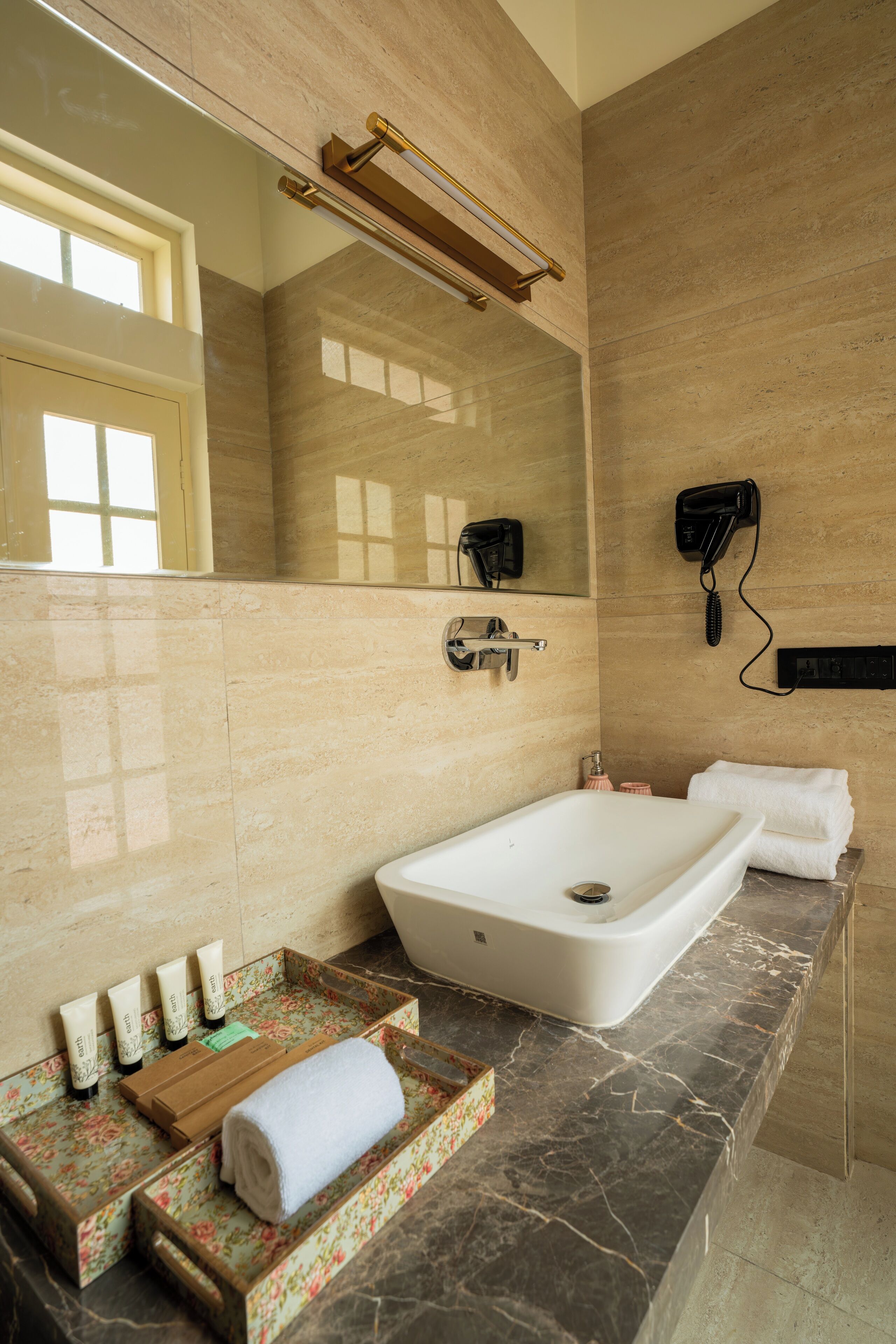 A bathroom with a large bathtub, a mirror, a hairdryer, and toiletries on the counter.
