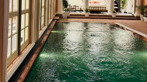 A swimming pool with a view of a room with a sofa and a chair, and a staircase leading to another level. - Dolce Vita - Luxury Vacation Villas (Pushkar)