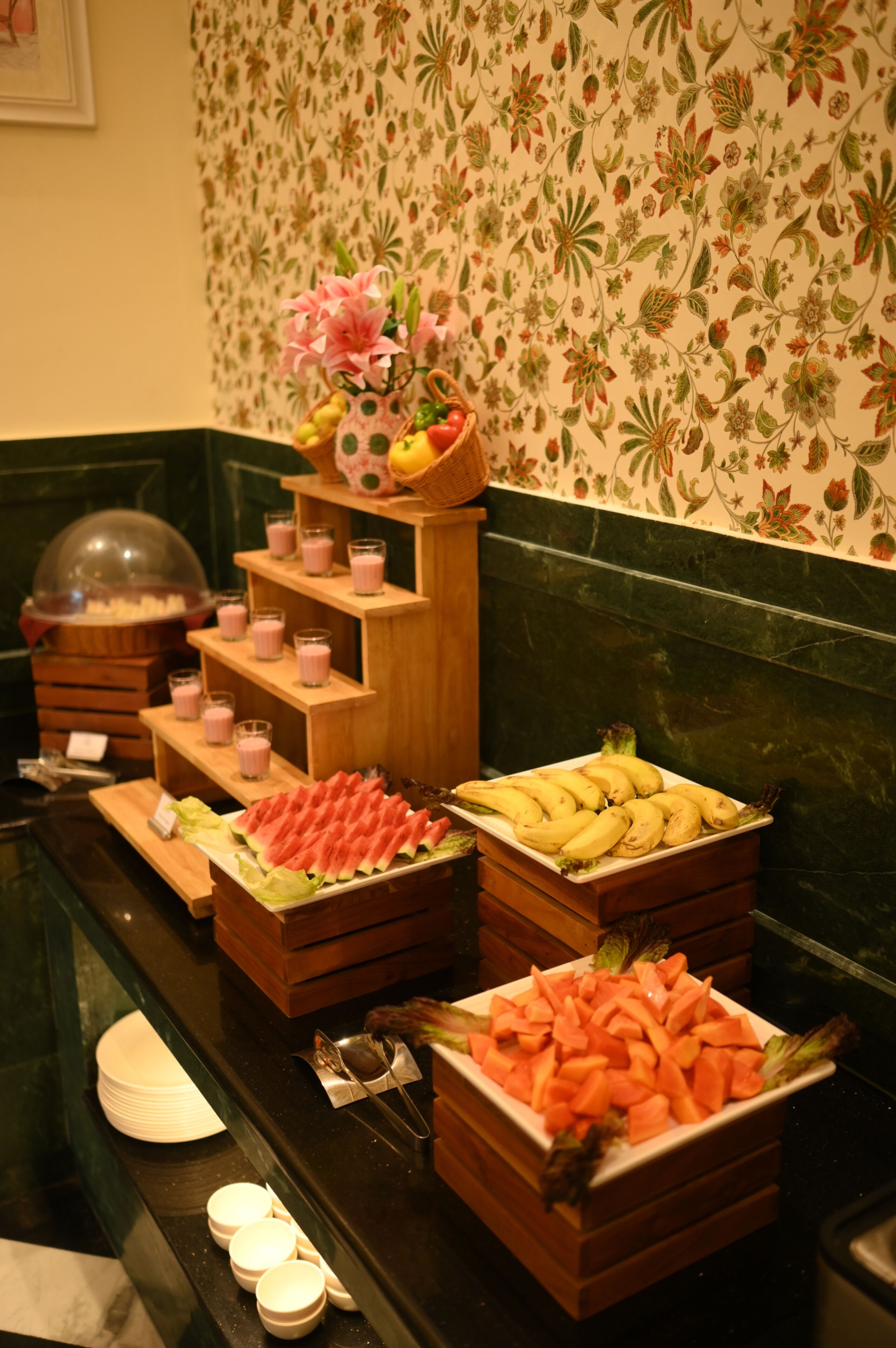 A buffet with various food items including fruits, vegetables, and a floral centerpiece.