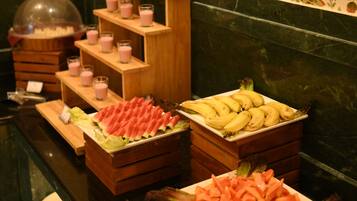 A buffet with various food items including fruits, vegetables, and a floral centerpiece.