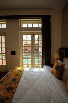 A hotel room with a bed, a view of a pool, and a balcony.