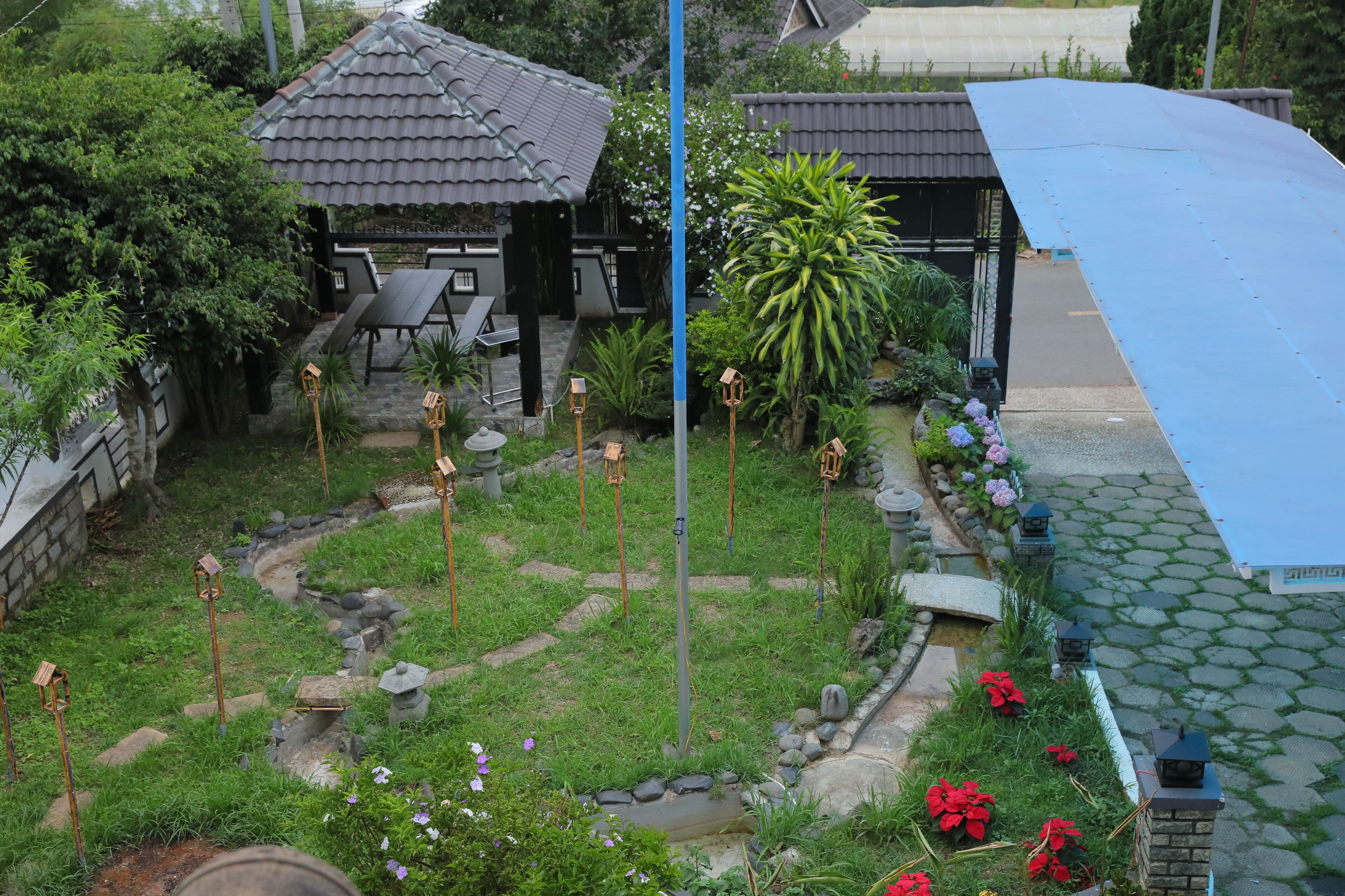 A garden with a gazebo, a small pond, and a pathway.