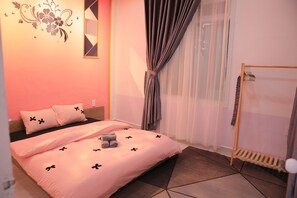 Ein Schlafzimmer mit einem Bett, Kissen, einem Nachttisch, einem Spiegel, Vorhängen, einem Fenster und einem Holztrockner.