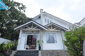 Ein zweistöckiges Haus mit weißer Fassade, Stein Fundament und einer Veranda mit Treppe.