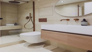 Une salle de bain moderne avec une douche à parois de verre, des toilettes blanches, un meuble-lavabo en bois avec un miroir et une petite étagère sur laquelle est posée une serviette.