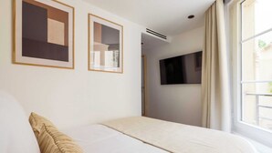 Une chambre d’hôtel avec un lit, un téléviseur fixé au mur et deux tableaux abstraits encadrés.