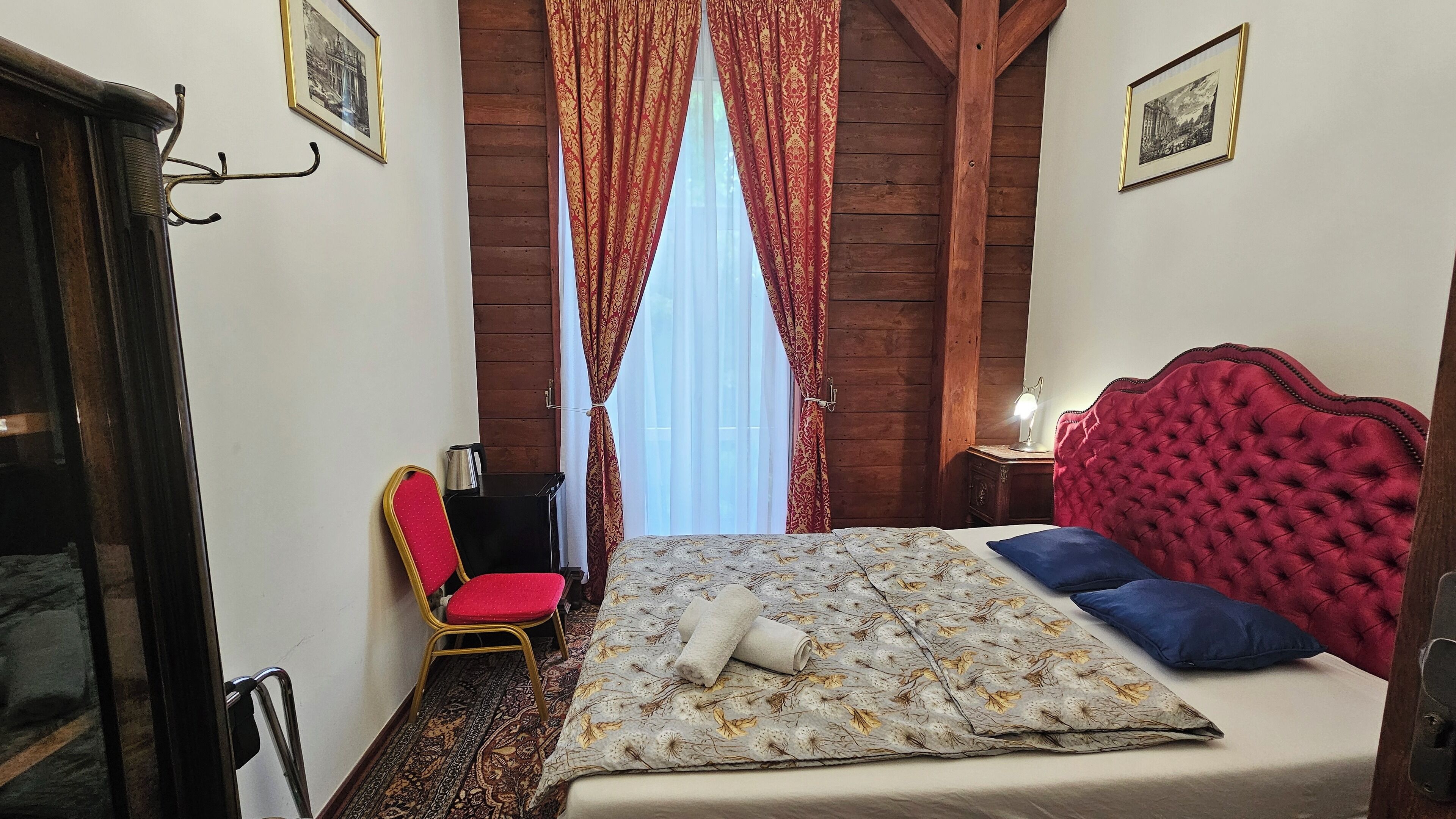 Une chambre à coucher avec un lit, une chaise, une table de chevet et une fenêtre avec des rideaux.
