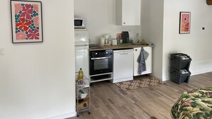 Eine kompakte Küche mit Mikrowelle, Backofen und Spüle, einem kleinen Kühlschrank und einem Mülleimer.